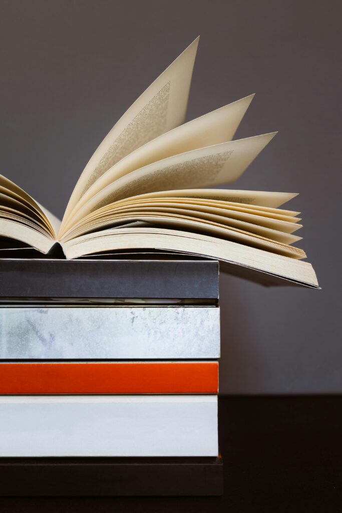 Close-up of an open book on top of pile of books showing half of empty book spine. Concept of reading, literature or knowledge